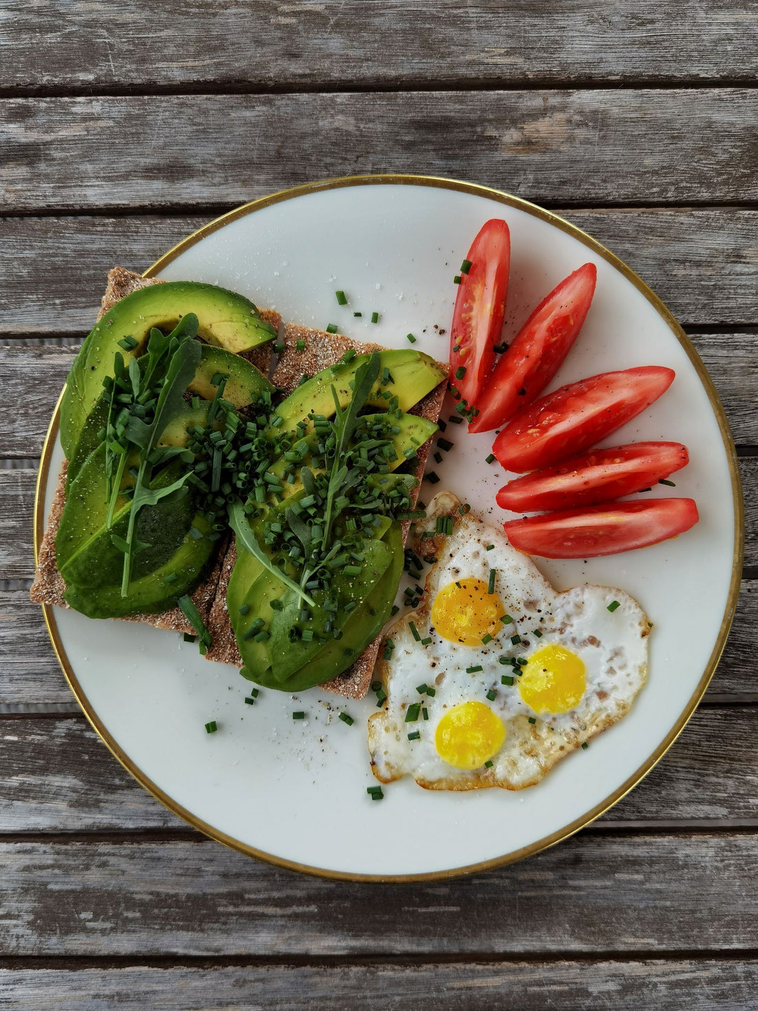 Avocado toast topped with fried quail eggs and tomatoes